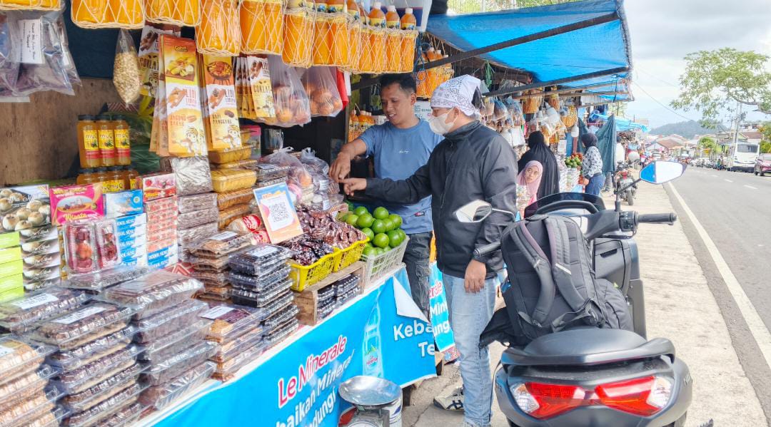 Seorang wisatawan memborong sejumlah oleh-oleh khas Malino di Sentra UMKM, menikmati aneka buah dan kerajinan lokal, Minggu (27/08/2025). (Foto: Mardianto/Kabareditorial.com)